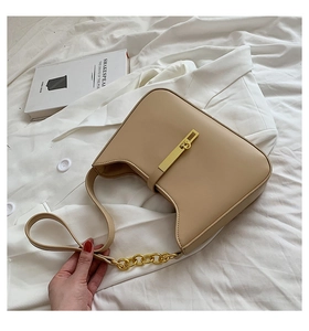 Detail view of beige crescent bag with gold buckle, chain strap and elegant matte finish