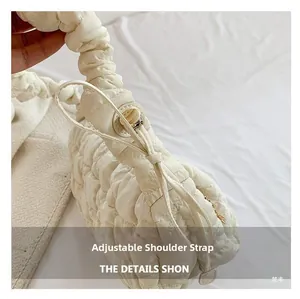 Detail of adjustable gathered strap and quilted texture on a beige puffy cloud bag