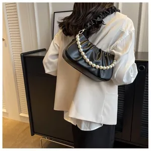 Detailed view of black pleated cloud bag with elegant large pearl chain handle on model