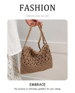 Détail d'un sac en paille tissé main avec motifs floraux ajourés et poignée tressée