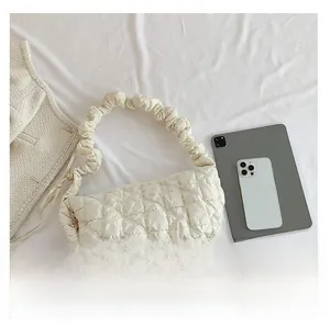 Close-up of white quilted puffer bag featuring a scrunchie shoulder strap and cloud texture