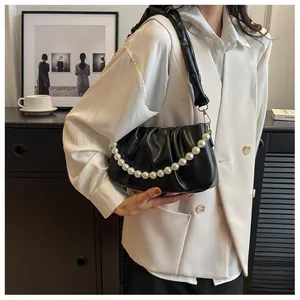 Detail view of black pleated cloud bag with elegant pearl chain and soft leather texture