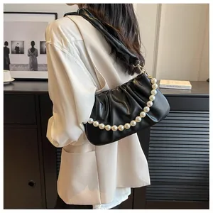 Close-up of black pleated cloud bag with elegant pearl chain on a modern shoulder strap