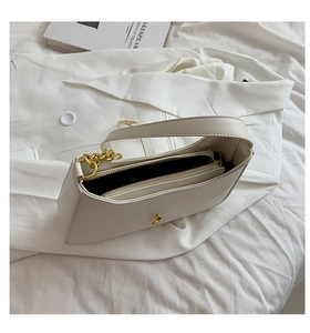 Detail view of white minimalist underarm bag with gold chain and matching inner pouch