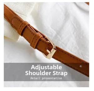 Close-up of adjustable brown leather shoulder strap with gold buckle and fine stitching