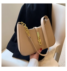 Detailed close-up of a beige crescent bag with gold chain and metal buckle on a chair