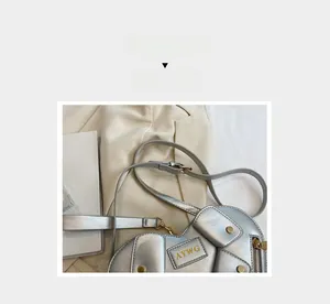Detail of silver heart shaped shoulder bag featuring metal zippers and logo patch