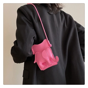 Détail du sac bandoulière éléphant rose vif en similicuir porté sur un blazer noir chic