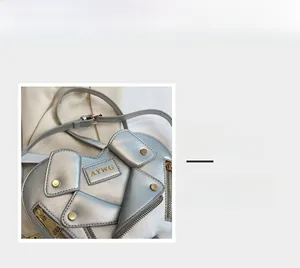 Detail view of silver heart-shaped crossbody bag featuring moto jacket zippers and studs