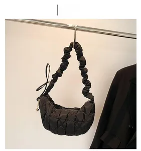 Detail of black quilted puffer bag with star pendant and pleated shoulder strap