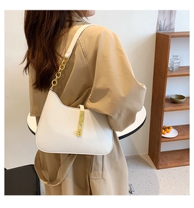 Detail of white crescent shoulder bag with gold chain strap and sleek metal buckle