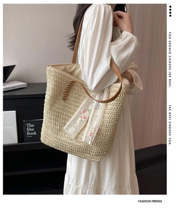 Close-up of handmade straw tote bag featuring delicate pink flower embroidery and lace trim