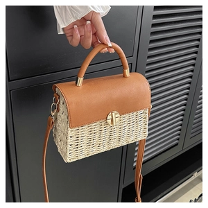 Detailed view of woven straw crossbody bag with brown leather flap and gold twist lock