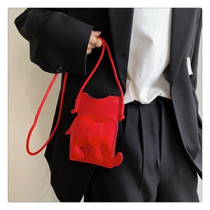 Sac à main chic en cuir rouge en forme d'éléphant porté avec un blazer noir élégant