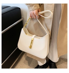 Detail of a chic cream leather underarm bag featuring a textured gold metal buckle and chain