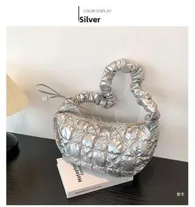 Detail of silver quilted cloud bag with pleated handle on a desk with vintage lamp