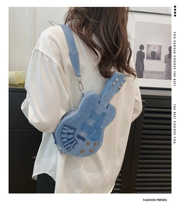 Detail of light blue denim guitar-shaped shoulder bag with stitching and metal buttons