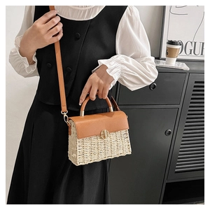Detail of hand-woven straw crossbody bag with brown leather flap and golden metal buckle
