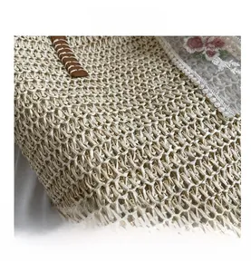 Detailed close-up of woven straw texture with white lace trim and floral embroidery