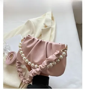 Detailed view of a soft pink ruched cloud bag with white pearl beaded handle and strap