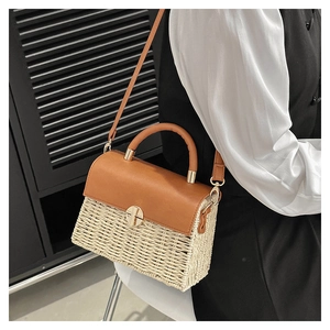 Detail of woven straw handbag with brown leather flap and round golden metal buckle