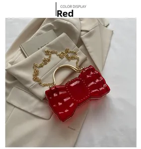 Détail du sac de soirée rouge en acrylique en forme de nœud avec chaîne dorée