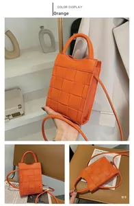 Detailed view of orange woven mini tote bag featuring chunky texture and rolled handle