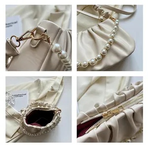 Detail view of beige cloud bag featuring golden hardware and luxury pearl chain strap