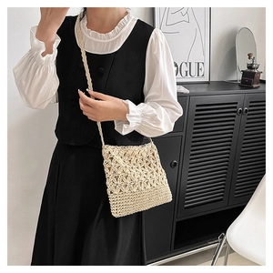 Détail du sac à bandoulière beige crocheté à la main avec motifs floraux sur un mannequin