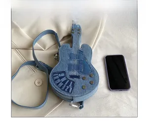Detail view of denim guitar-shaped crossbody bag with rivets and phone for size comparison