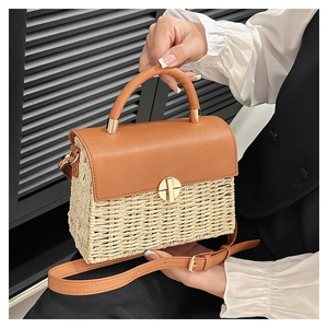 Detail of woven straw and brown leather shoulder bag with golden metallic clasp