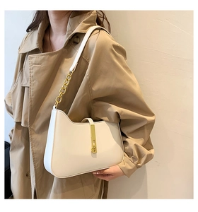 Detail of trendy off-white shoulder bag with golden metal buckle and chain strap