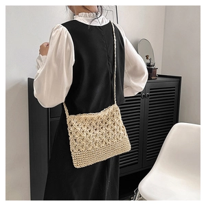 Détail du motif floral tissé main sur un sac bandoulière en paille de couleur beige