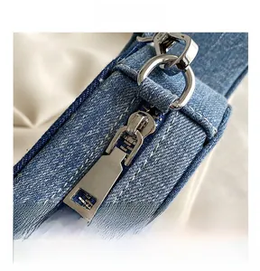 Detail of smooth silver metal zipper and hardware on guitar-shaped denim crossbody bag
