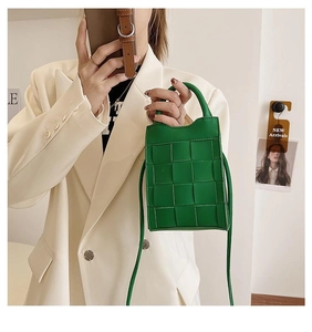 Close-up of green woven leather handbag texture with top handle and shoulder strap