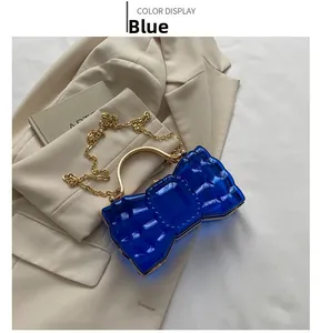Détail de la pochette nœud en acrylique bleu avec poignée dorée sur blazer beige