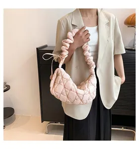 Detail of light pink quilted moon bag with ruched handle and silky satin texture