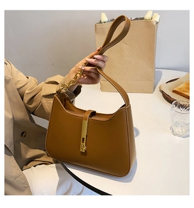 Close-up of caramel brown shoulder bag with golden metal buckle in a lifestyle setting