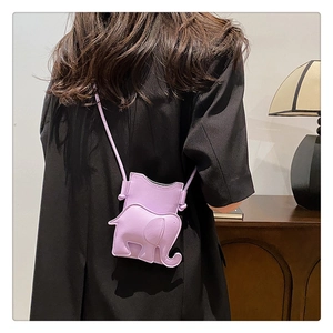 Détail du mini sac bandoulière éléphant violet porté par un mannequin dans un décor chaleureux