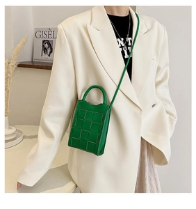 Detail of a bright green woven mini crossbody bag with a round handle and PU leather texture