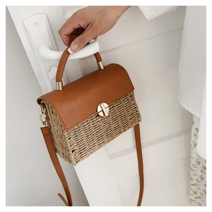 Detail of woven straw and brown leather shoulder bag with golden metal twist lock
