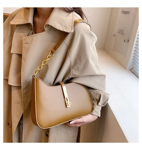 Detail of tan half-moon shoulder bag with golden metallic clasp and chain strap