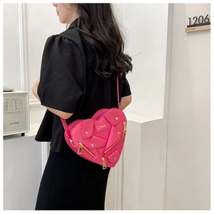 Detail of pink heart-shaped crossbody bag featuring motorcycle jacket zippers and metal logo