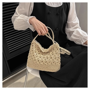 Détails du tissage floral artisanal et des anses robustes sur un sac en paille beige