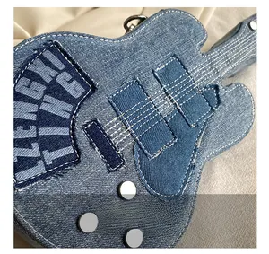 Macro detail of guitar-shaped denim bag featuring white topstitching and metal rivets