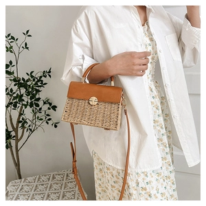 Detail of summer woven handbag featuring brown leather trim and golden metal swivel lock