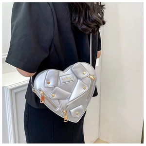 Detail of silver heart-shaped crossbody bag featuring motorcycle jacket design elements
