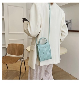 Detail of mint green woven crossbody bag with PU leather texture and hand straps