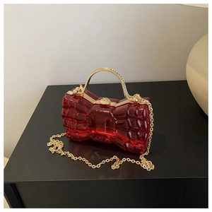 Vue détaillée du sac de soirée rouge en acrylique avec anse dorée et bandoulière