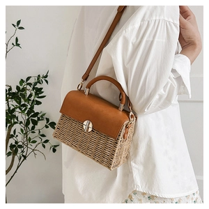 Close-up of woven straw handbag with brown faux leather flap and metal turn-lock